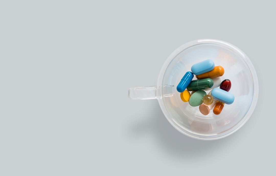 A transparent coffee cup with colourful pills on gray background. Dangerous virus. Virus epidemic concept. Tablets, Medicine and healthy. Close up of capsules. Differend kind of pills. Copy space
