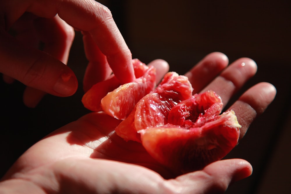 Persona sosteniendo una fruta roja en rodajas