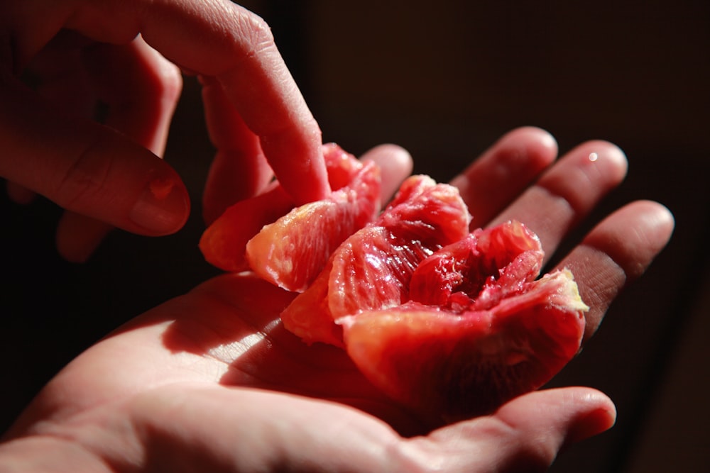 personne tenant des fruits rouges tranchés