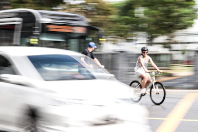 A content creator filming a cyclist commuting through city streets with bike gear in focus.