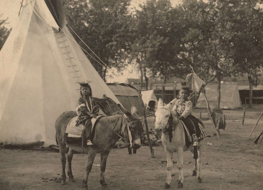 grayscale photo of people riding horses