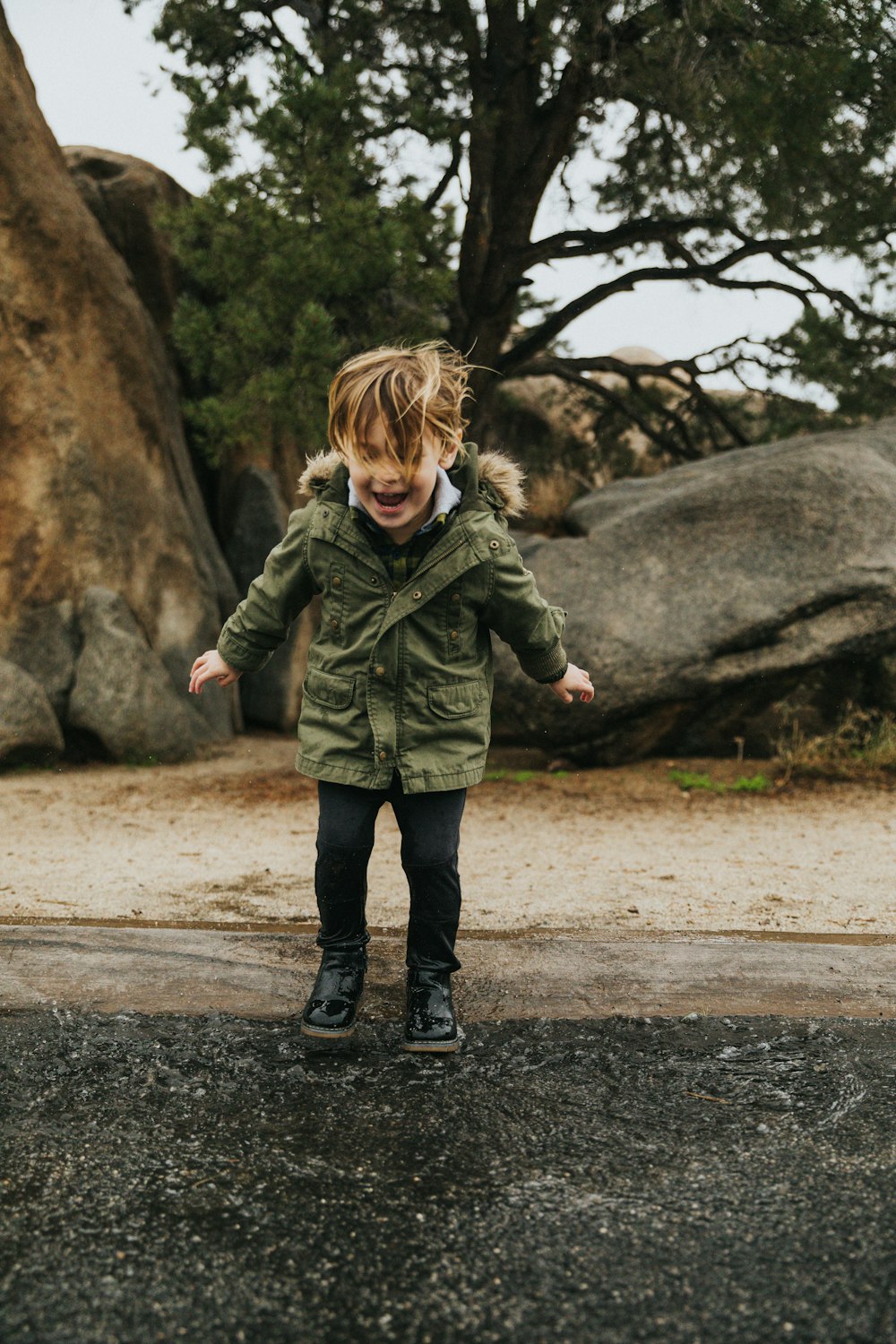 girl in green jacket walking on road during daytime