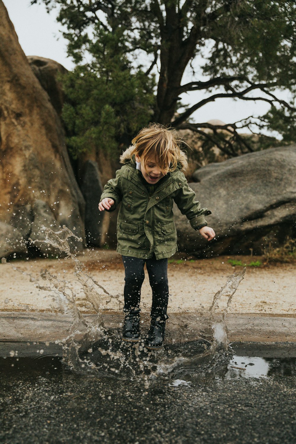 girl in green jacket standing on water