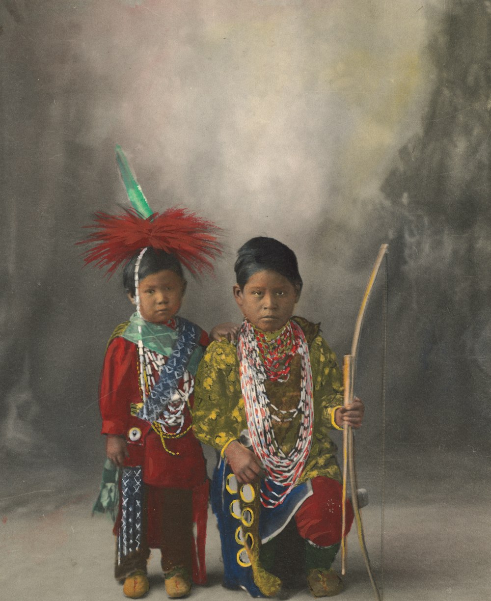 2 women in traditional dress holding stick