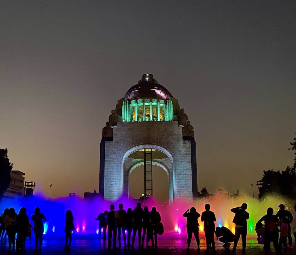 people standing near white concrete building during night time