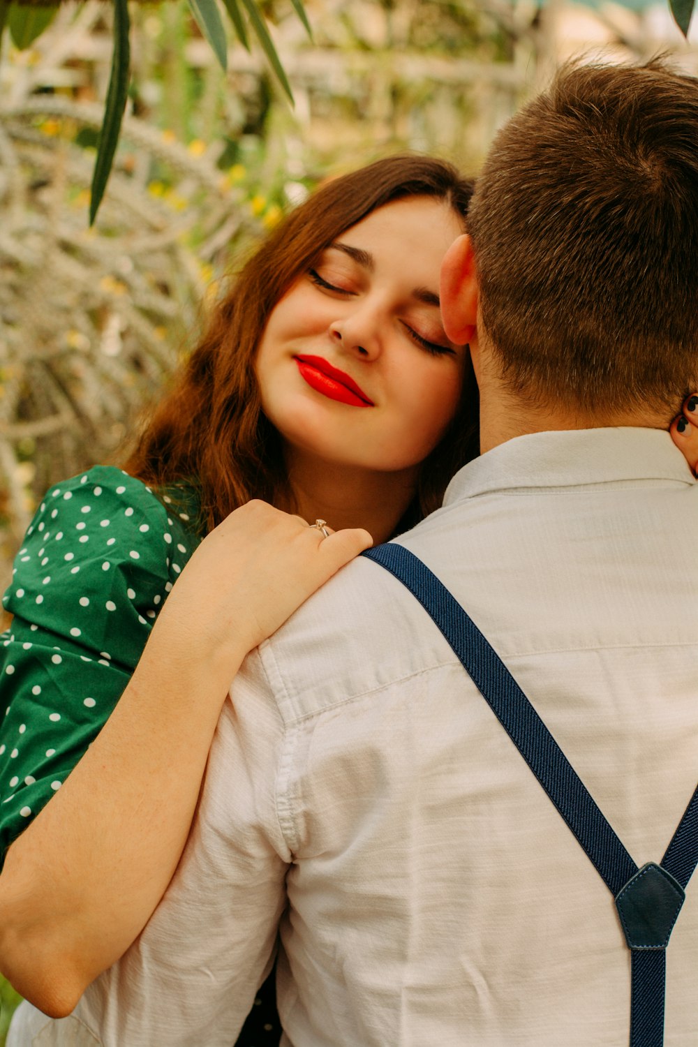 man in white dress shirt kissing woman in green and white floral dress