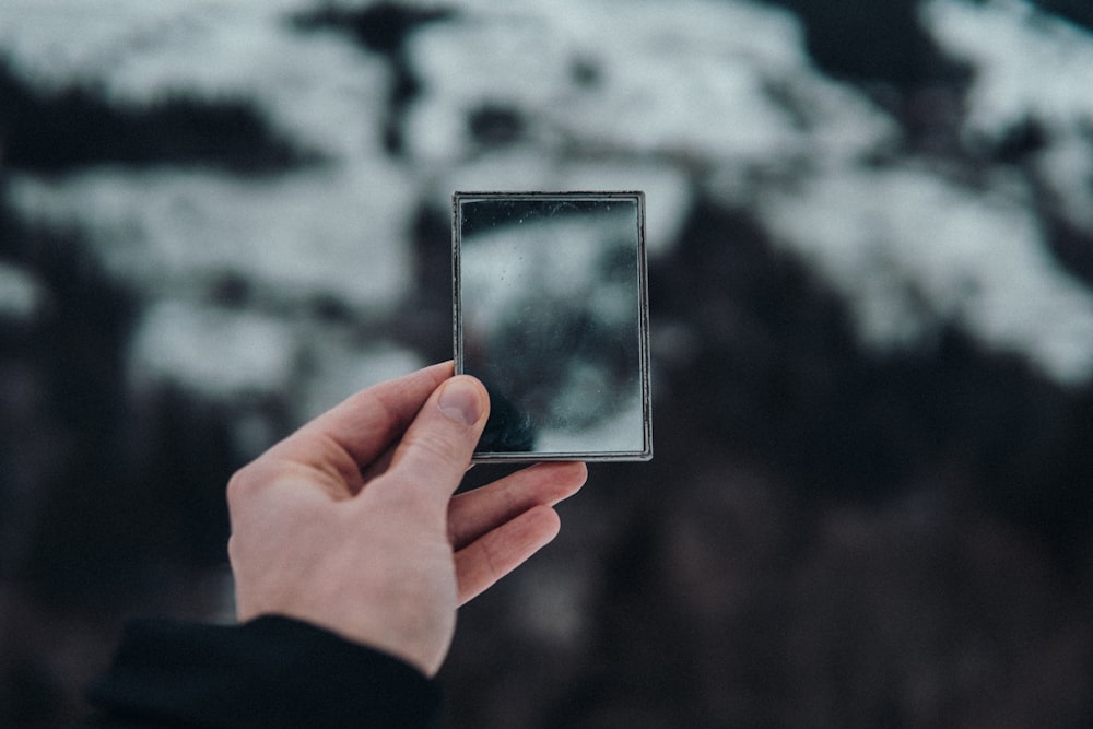 person holding silver square frame