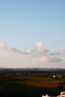 A serene landscape of a farm with green fields and a clear blue sky.