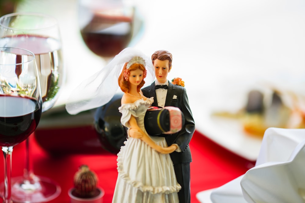 woman in white dress holding man in black suit figurine
