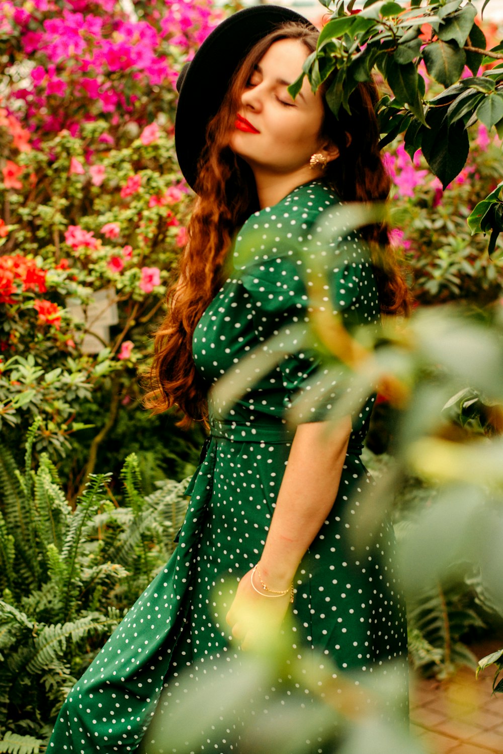 Frau in grünem Kleid in der Nähe von rosa Blumen