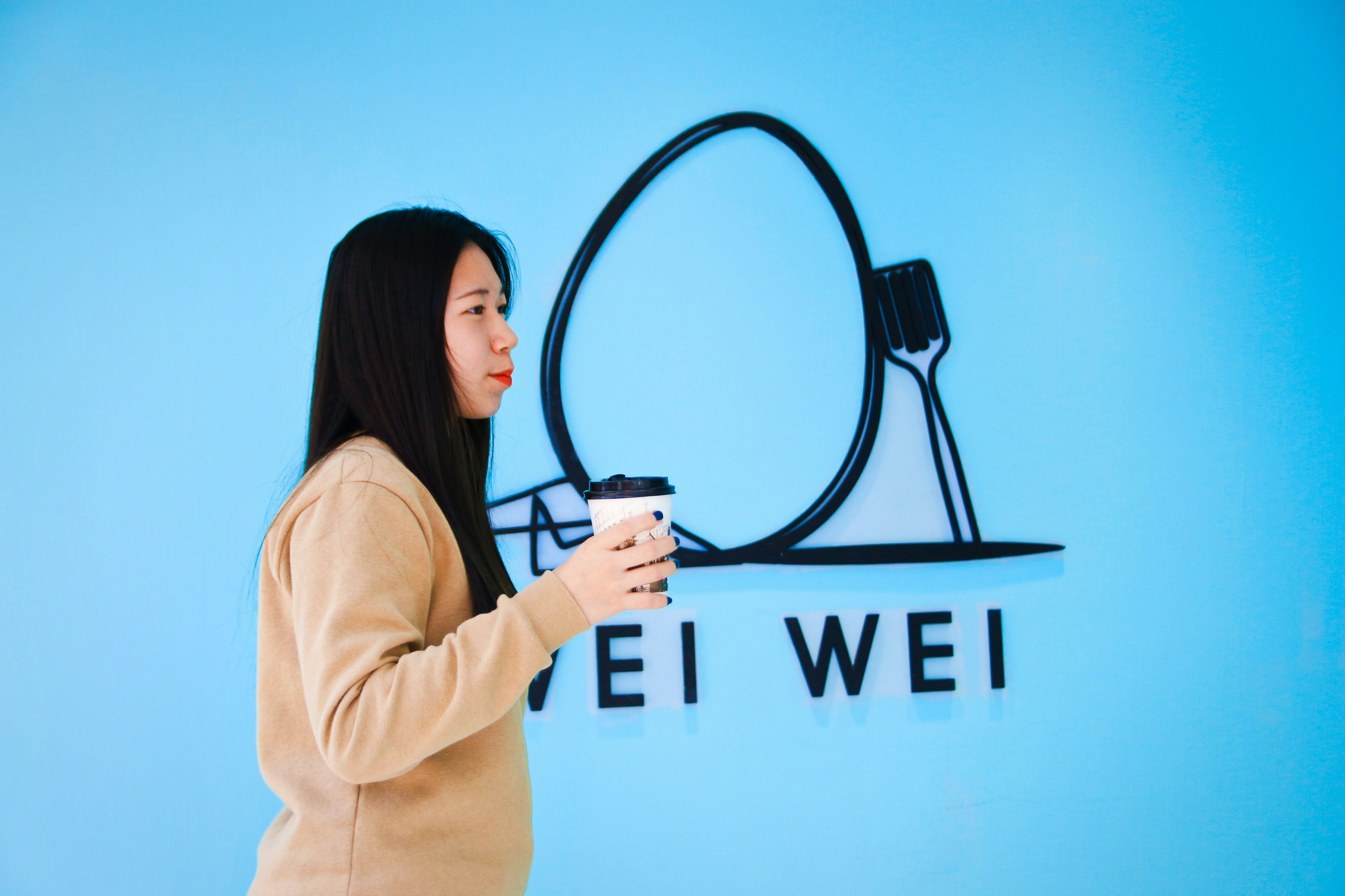 woman in beige long sleeve shirt holding black headphones