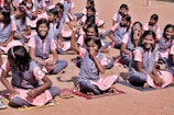 group of women sitting on brown sand during daytime