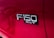 A close-up view of a red vehicle's side panel with the badge 'F-150 XLT' prominently displayed in chrome letters against a black background.