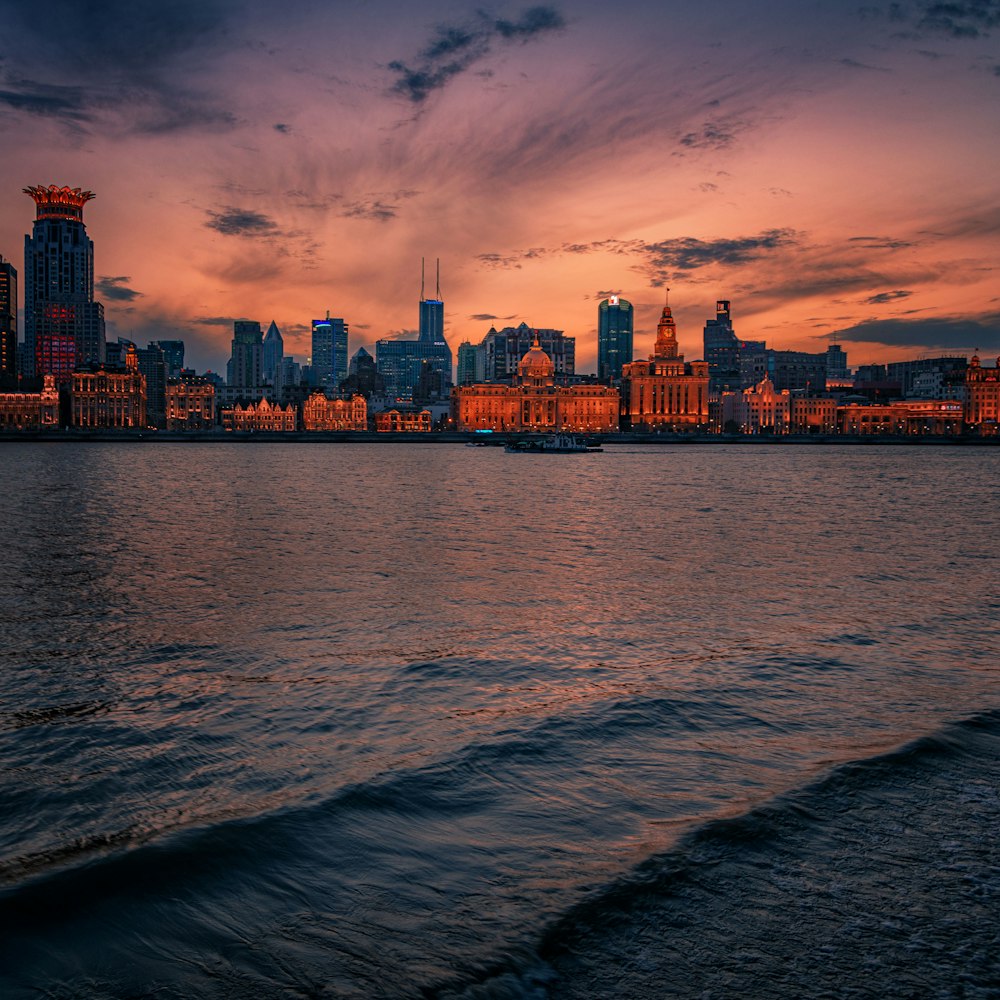 city skyline across body of water during sunset