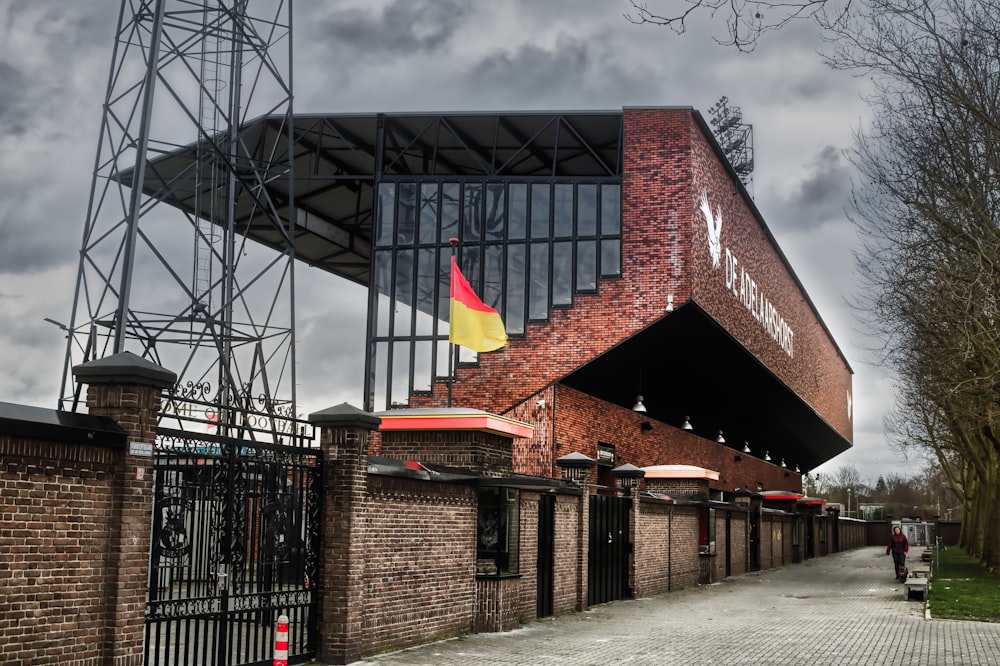 brown brick building with flags on roof under gray cloudy sky