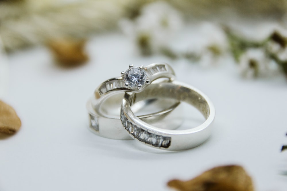 silver diamond ring on white surface