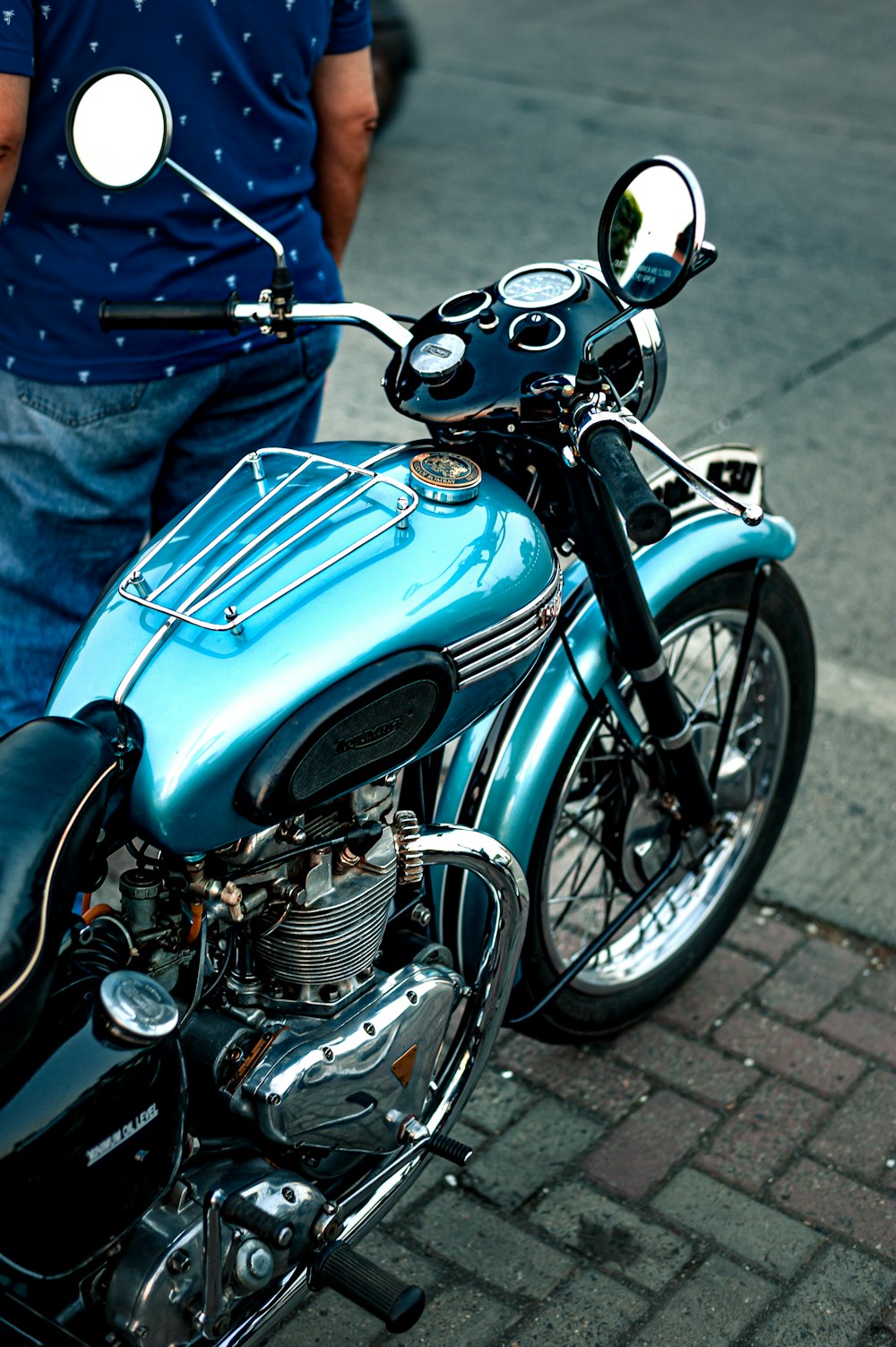 person in blue denim jeans standing beside blue and silver cruiser motorcycle