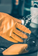 person in yellow shirt pouring water on clear glass