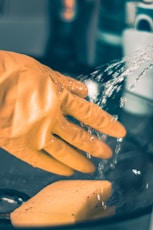 person in yellow shirt pouring water on clear glass