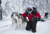 woman in black jacket and red backpack holding white and black siberian husky on snow covered