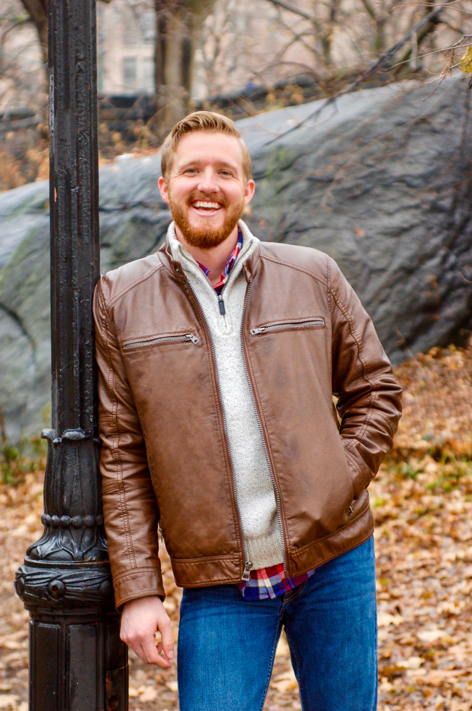 a man standing next to a lamp post in a park