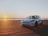 A modern rental car parked on a sunny beach.