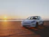 A sleek white luxury car parked in front of a charming wedding venue at sunset.