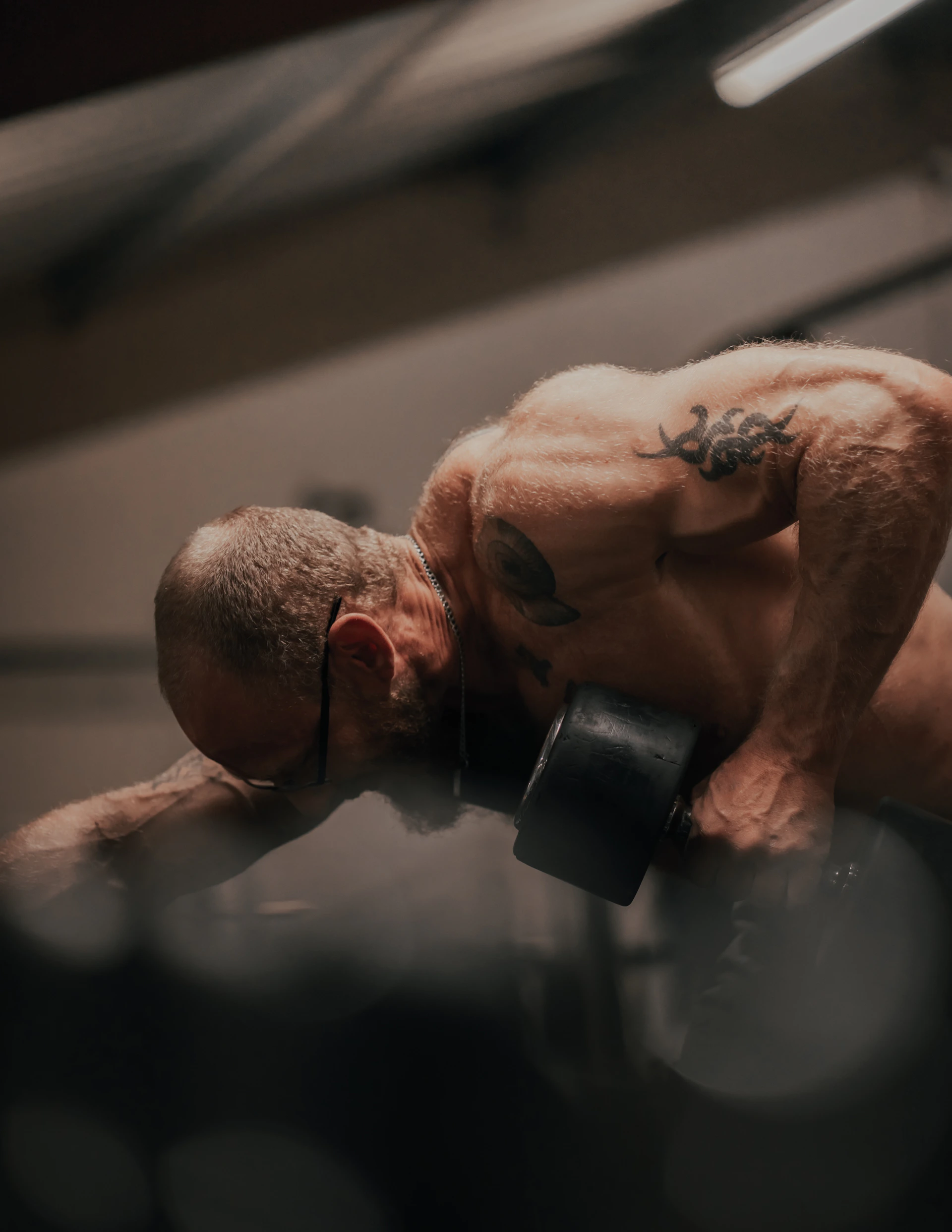 topless man holding black dumbbell