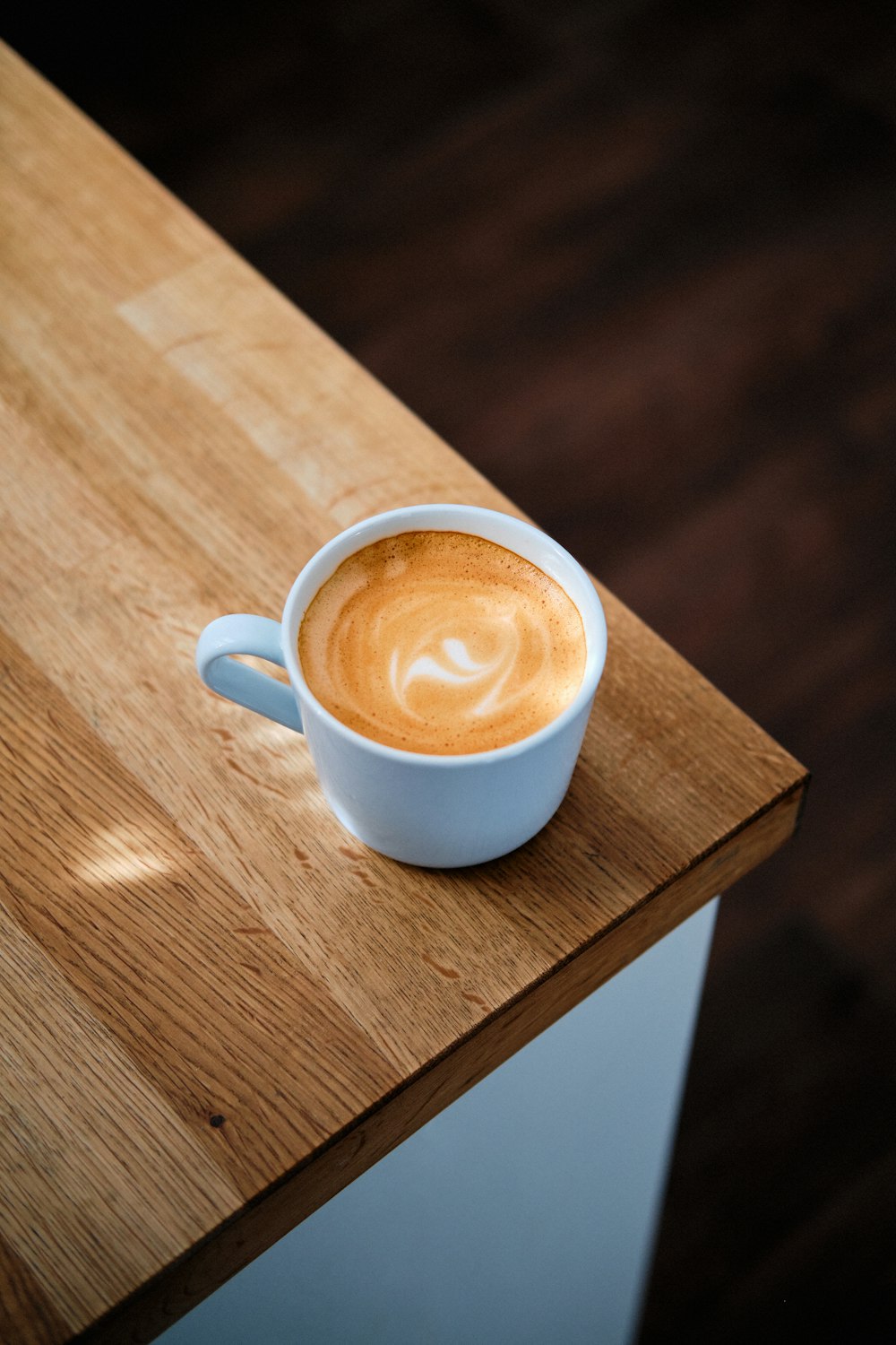 white ceramic mug with brown liquid on brown wooden table