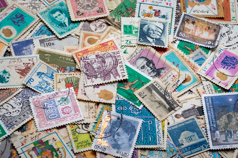 Close-up of a vintage stamp collection spread out on a wooden table, showing intricate designs and vibrant colors.