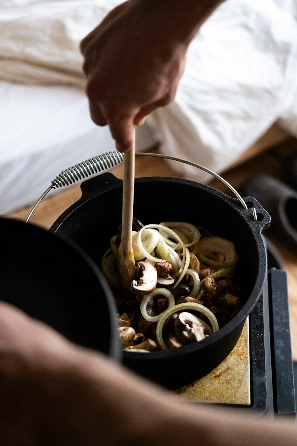 person holding black cooking pot with pasta