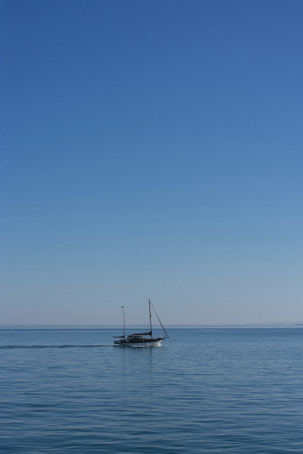 white sailboat on sea under blue sky during daytime