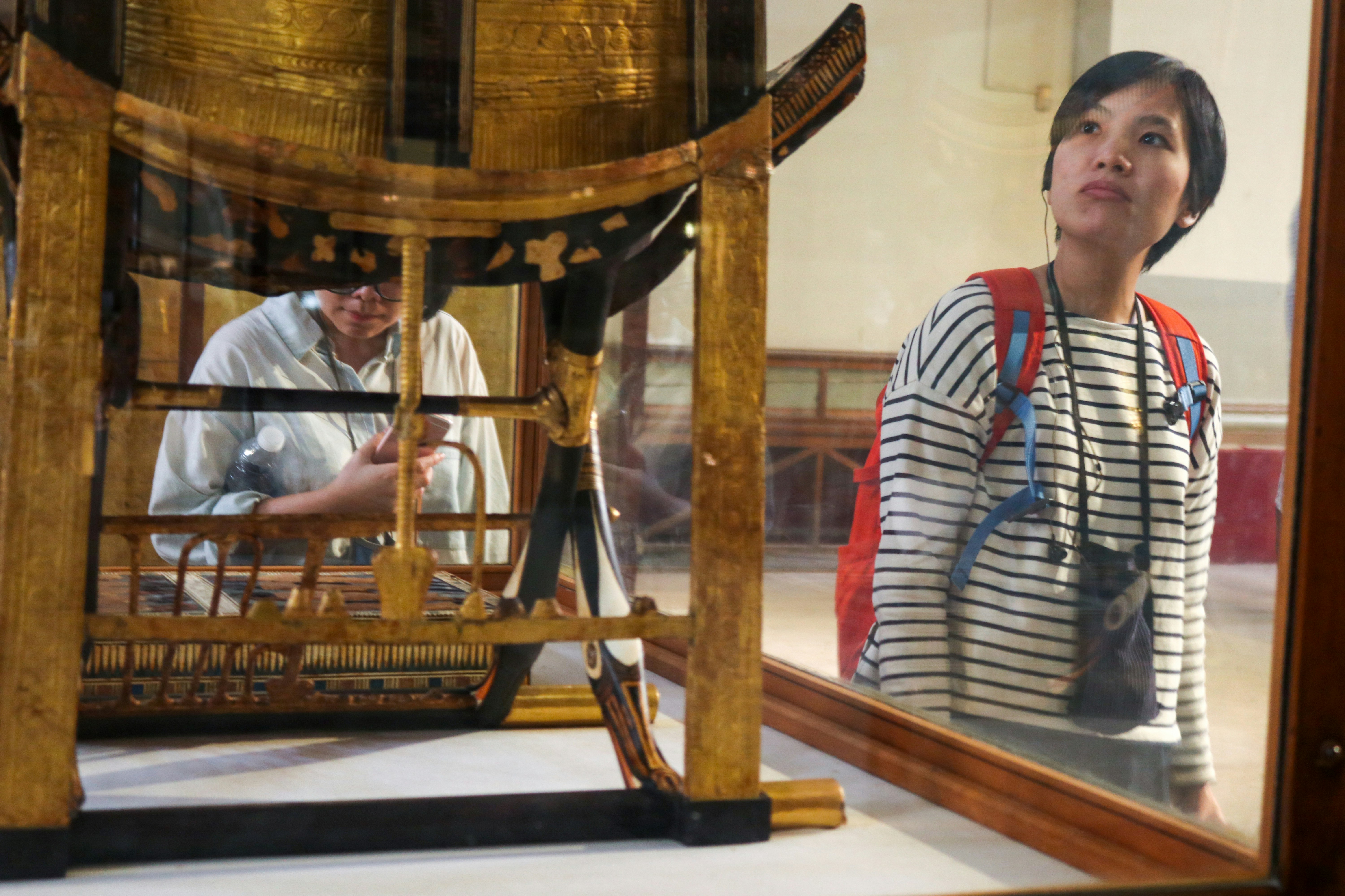 Man in red white and black striped polo shirt standing beside brown wooden table