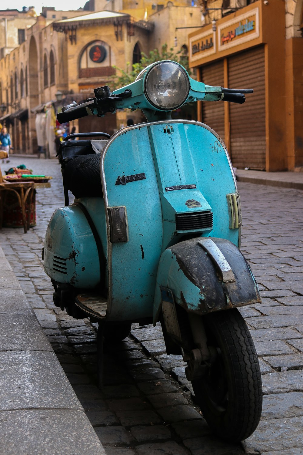 blue and black motor scooter parked on sidewalk during daytime