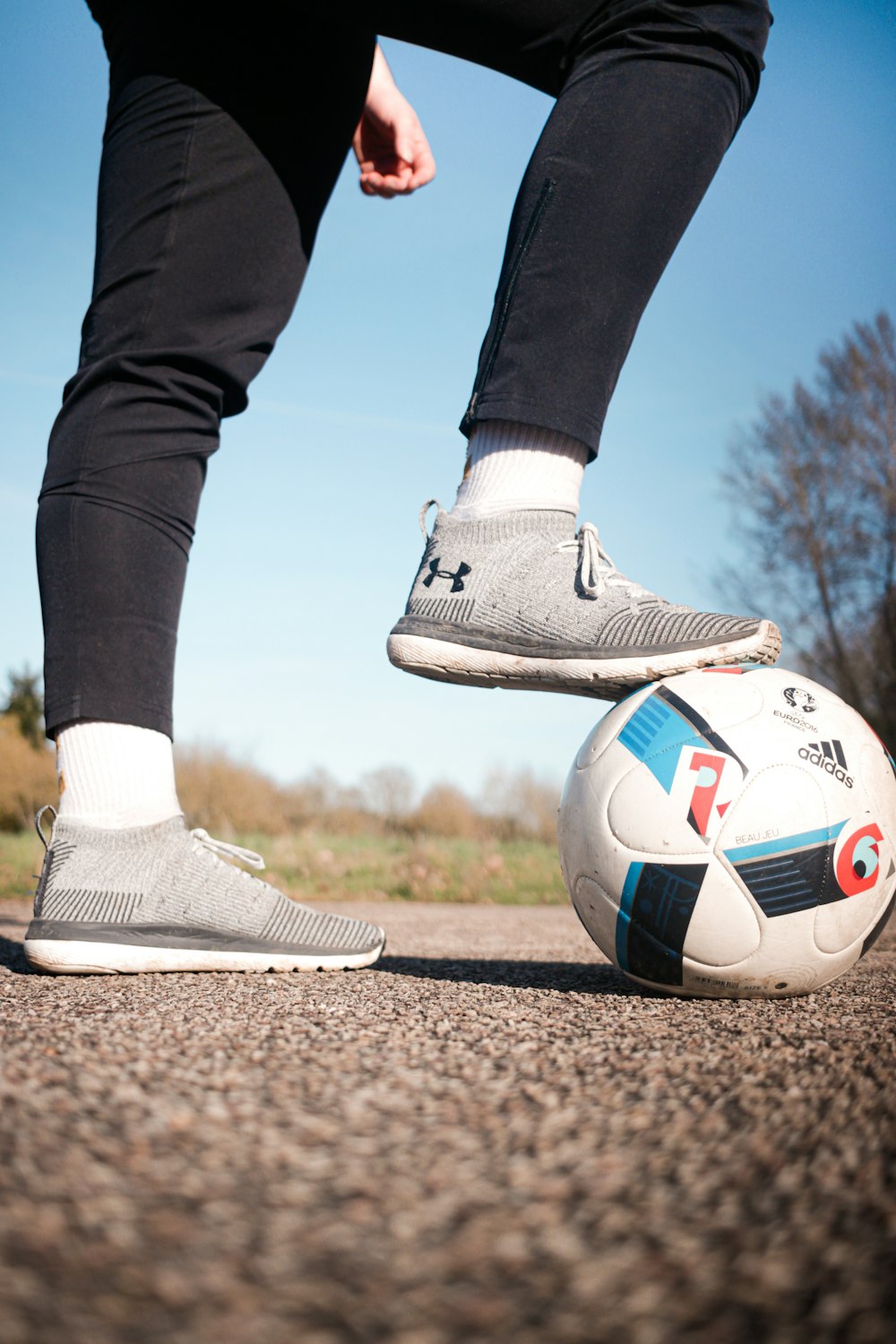 person in black pants and white nike soccer shoes