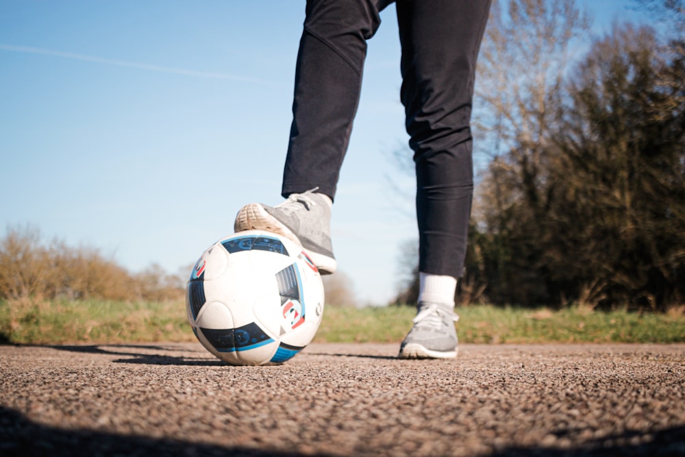 person in black pants and white nike soccer ball