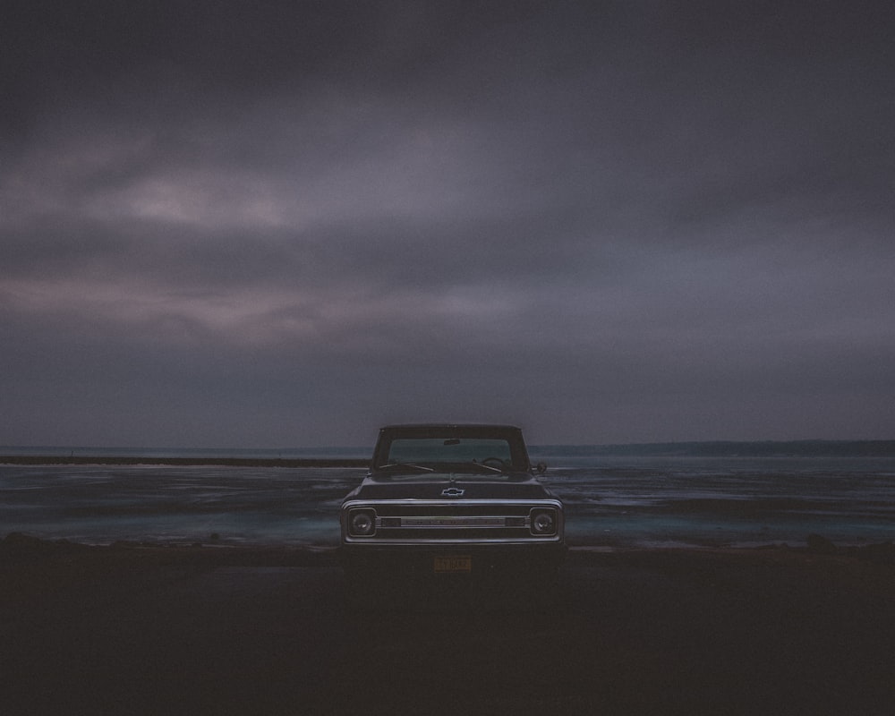 Coche Chevrolet negro en la playa durante el día