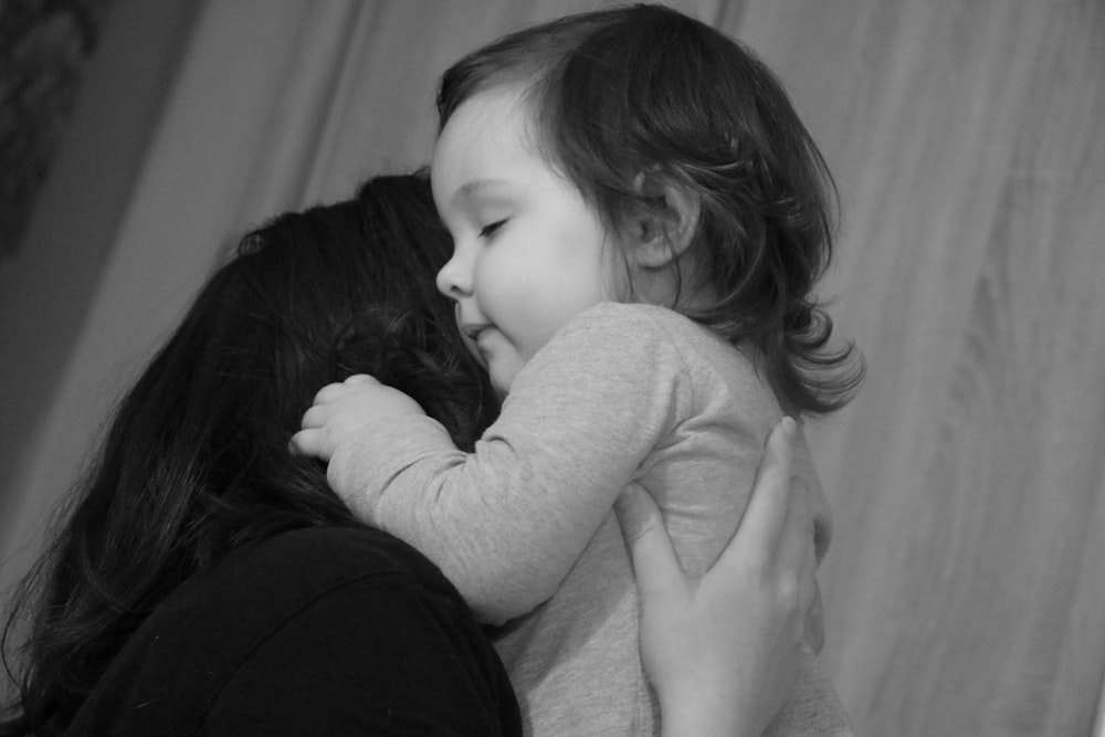 woman in black long sleeve shirt carrying baby in white long sleeve shirt