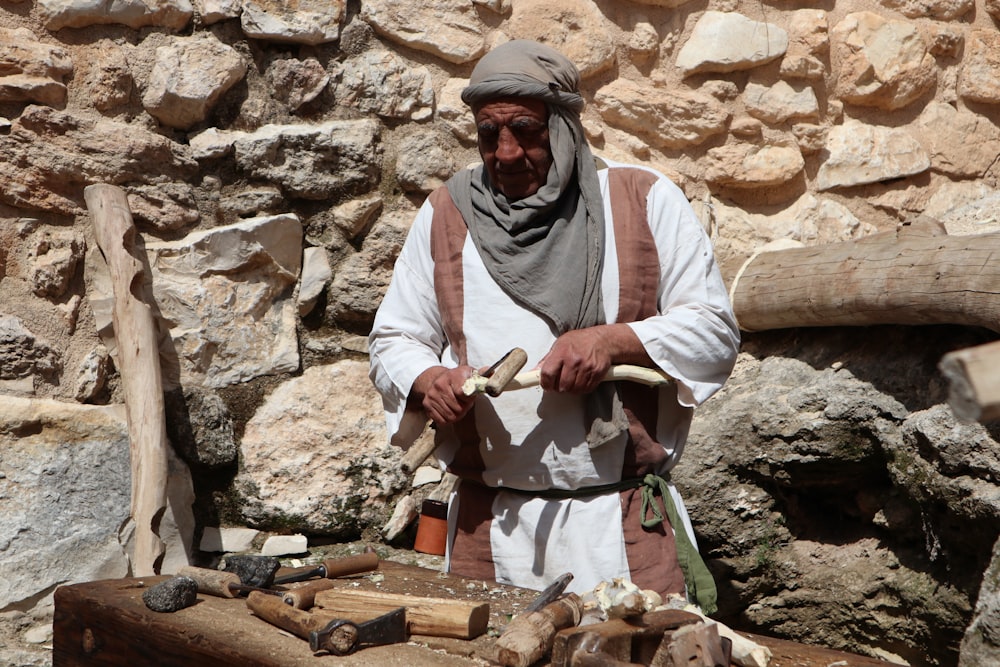 man in white long sleeve shirt and blue pants holding brown wooden stick