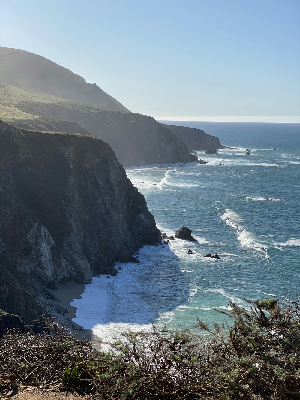 green and brown mountain beside sea during daytime