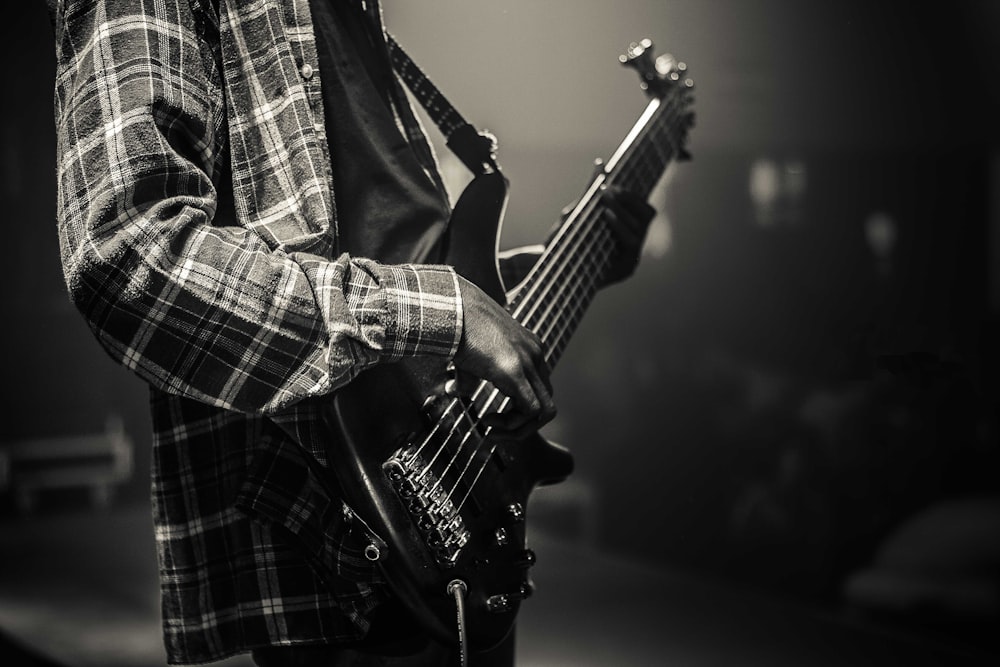 grayscale photo of man playing electric guitar