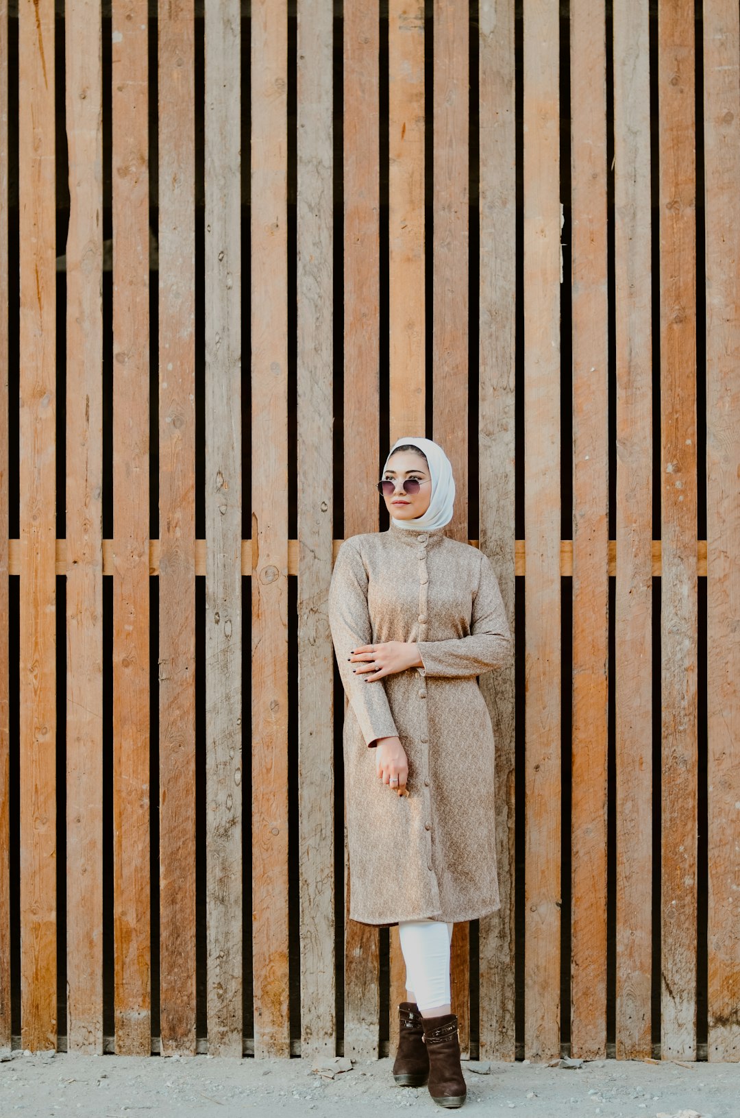 woman in white hijab standing beside brown wooden fence