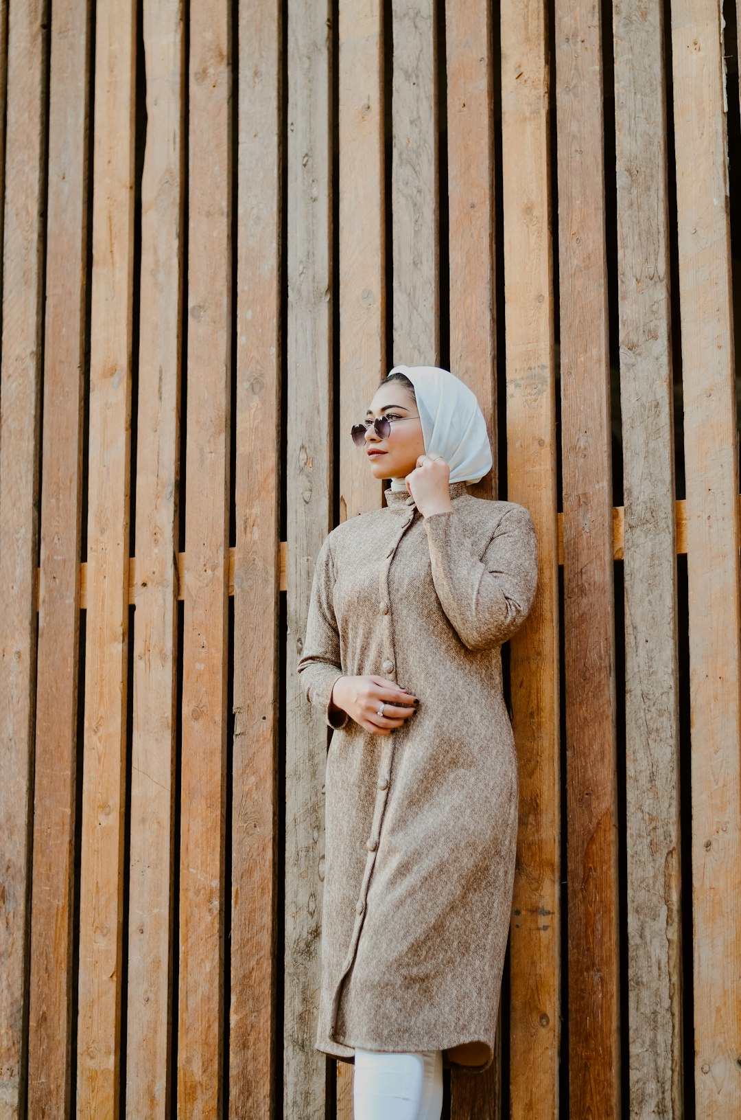 woman in beige sweater standing beside brown wooden wall
