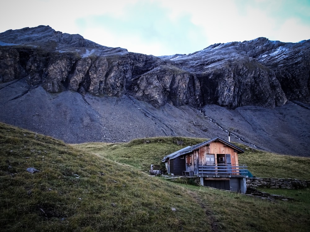 Braunes Holzhaus auf grünem Grasfeld in der Nähe von Gray Rocky Mountain tagsüber