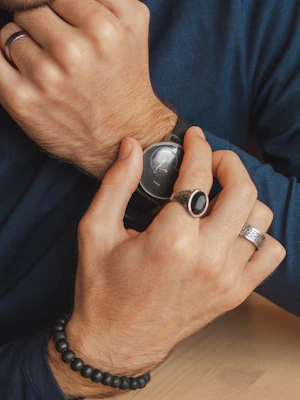 A woman accessorizing with a sleek watch and minimalist jewelry in a cozy cafe.