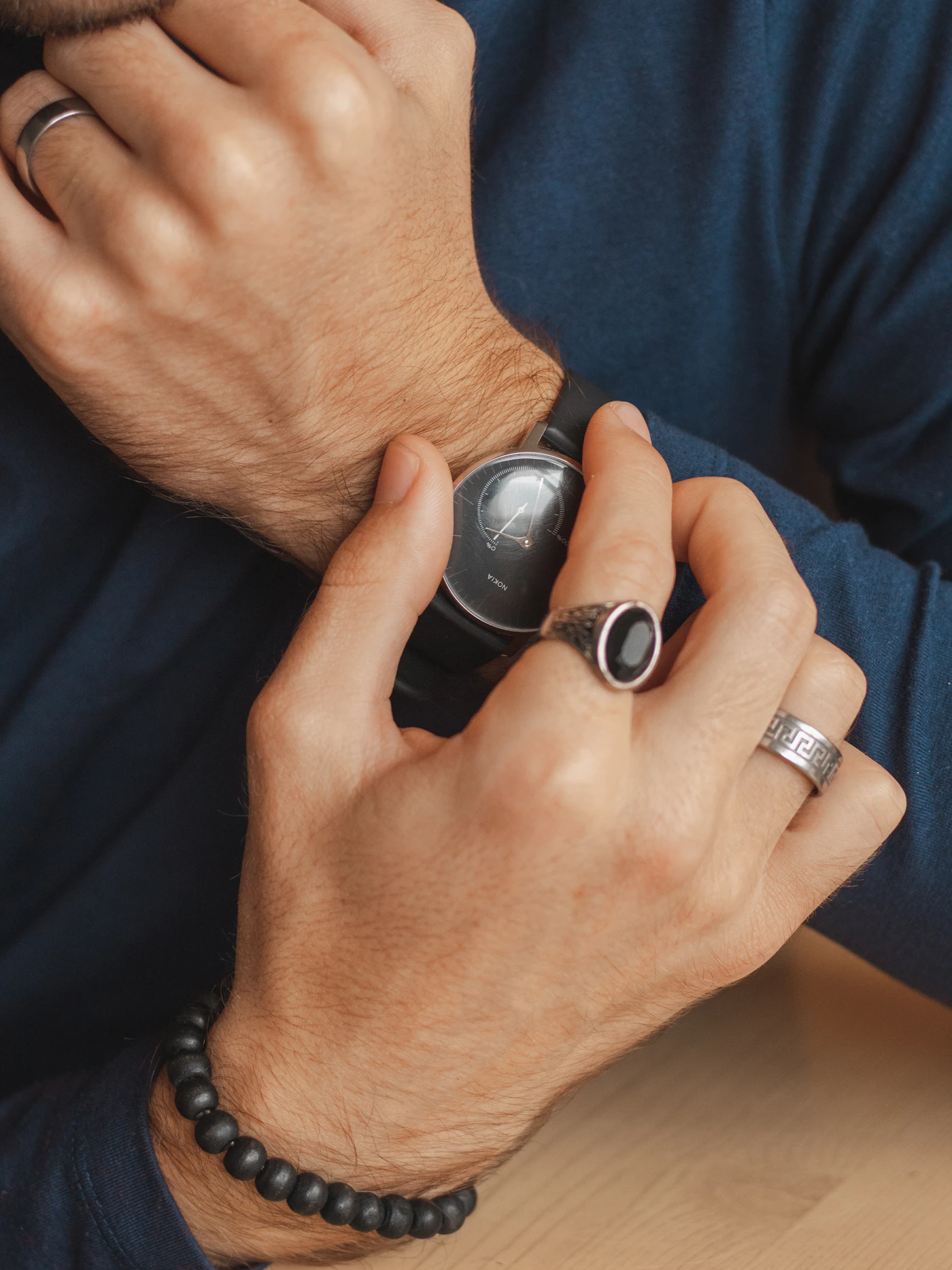 Hand wearing a silver ring set with a black stone