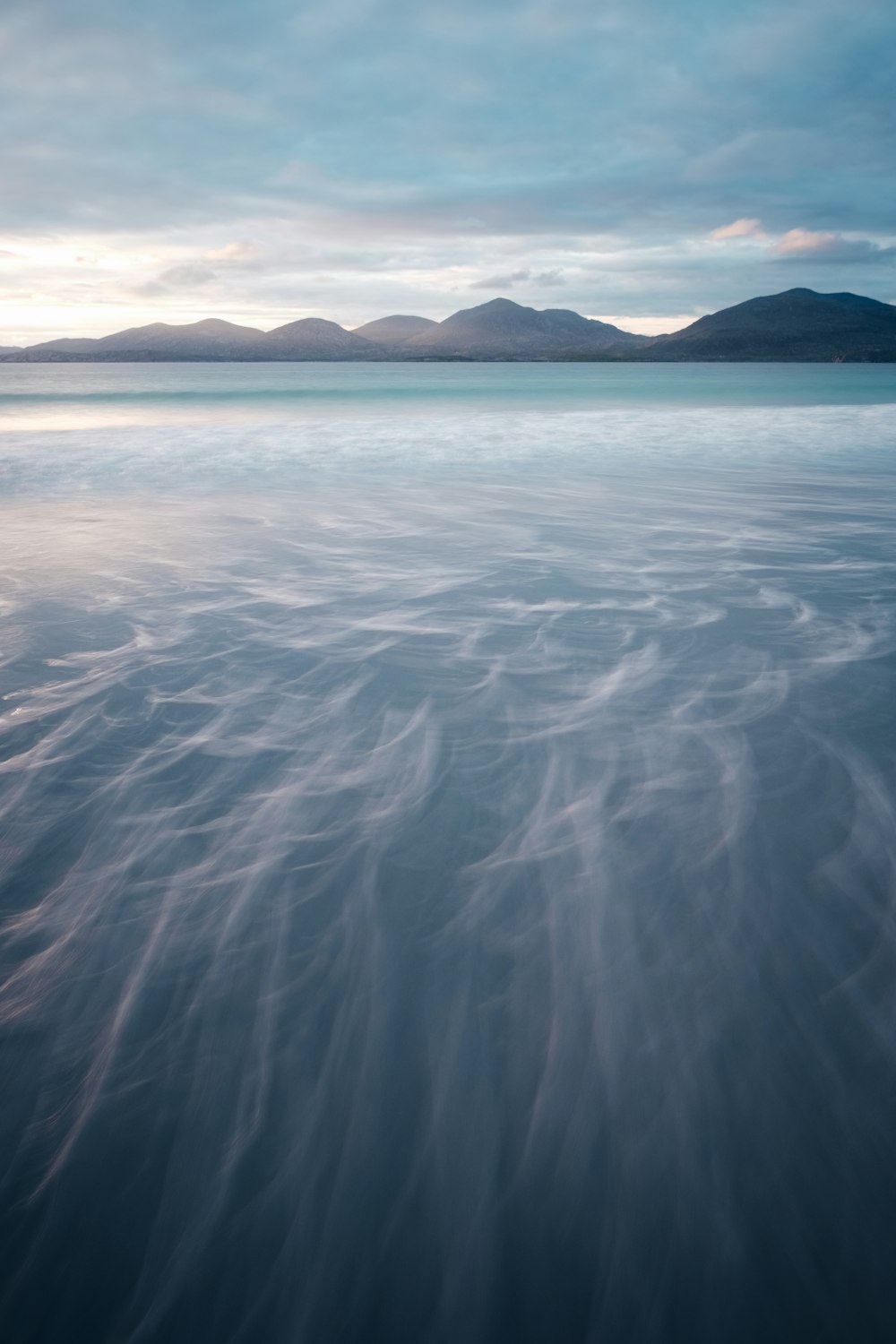 body of water near mountain during daytime