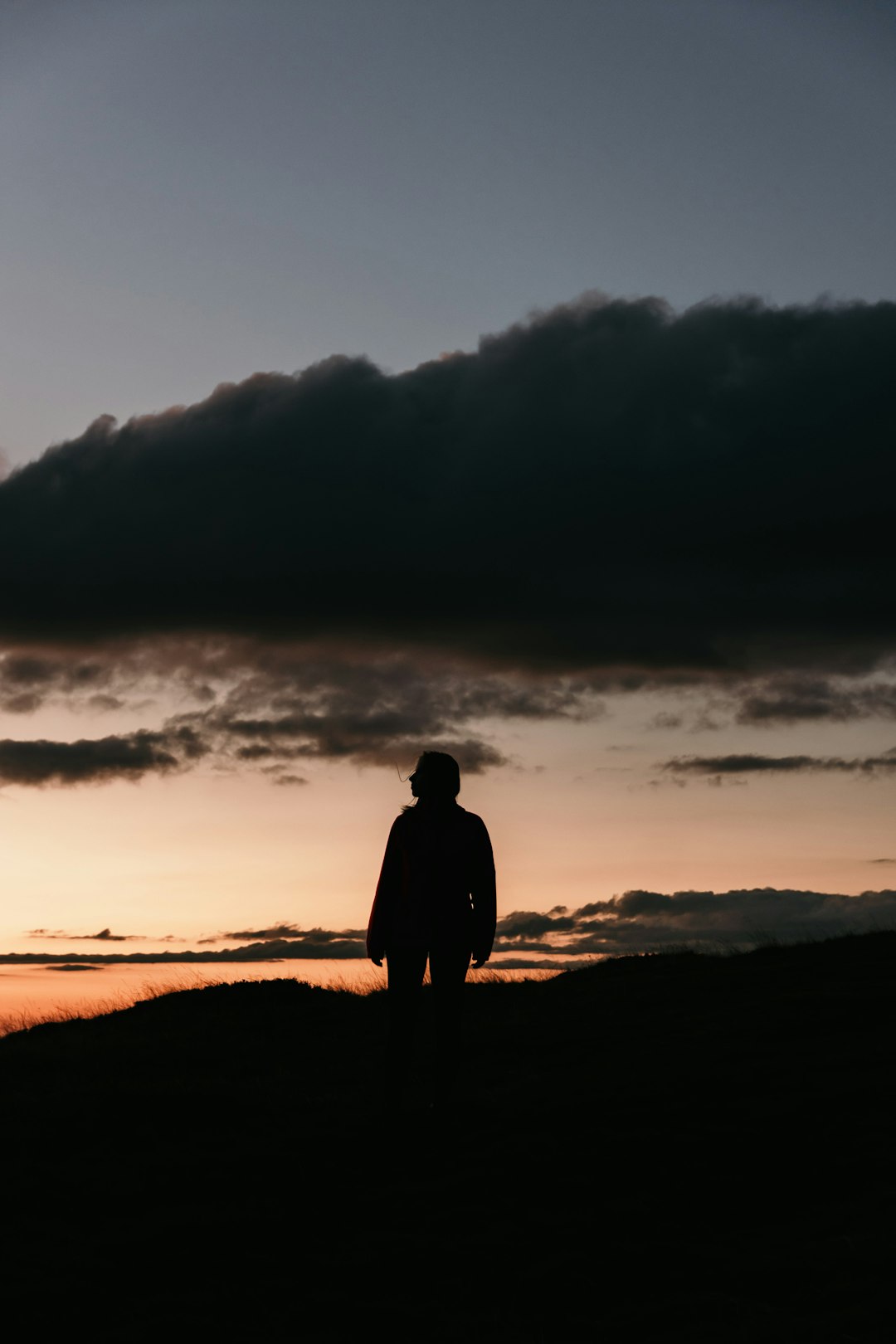 silhouette of man standing on seashore during sunset