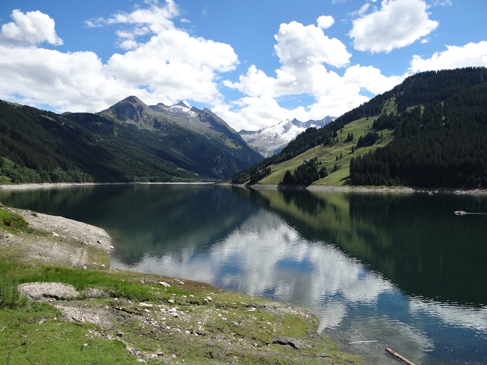 Lago vicino a montagne verdi sotto cielo blu durante il giorno