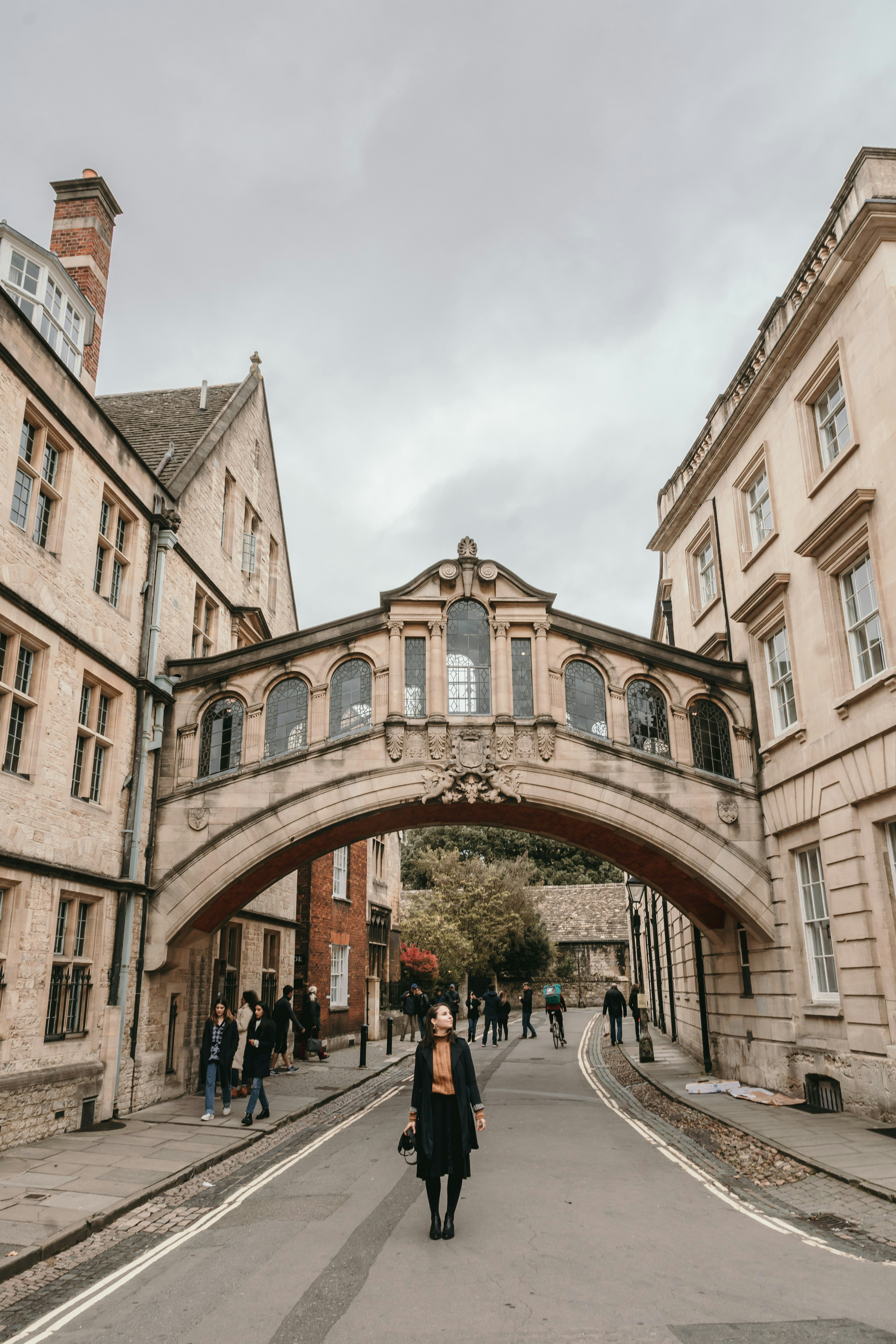 personnes marchant sur le trottoir près d’un bâtiment en béton brun pendant la journée